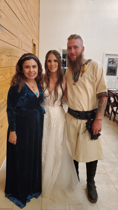 Oficiante con pareja en boda vikinga posando en interior con vestimenta temática